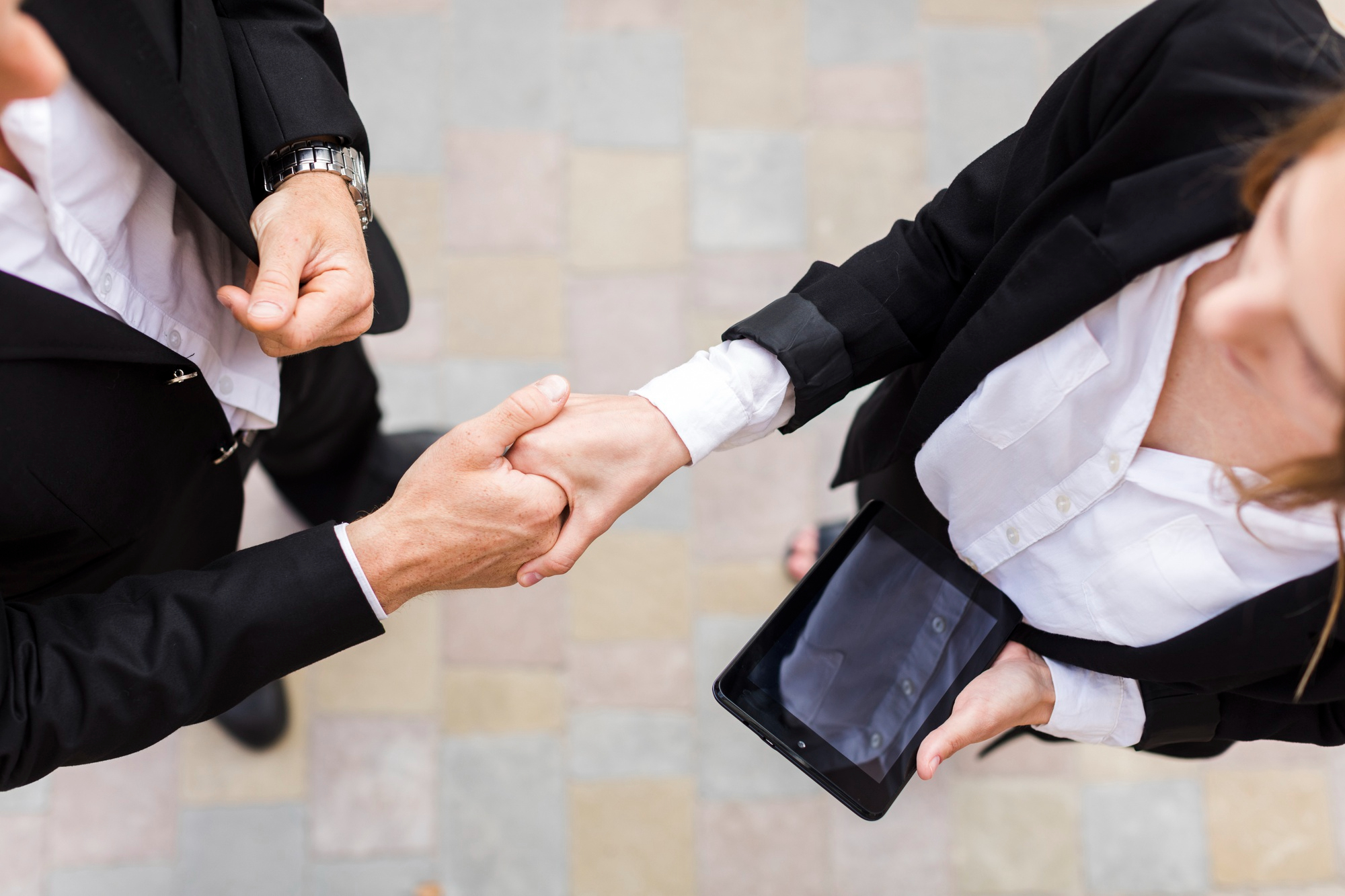 Aperto de mãos entre sócios simbolizando a fusão de empresas.